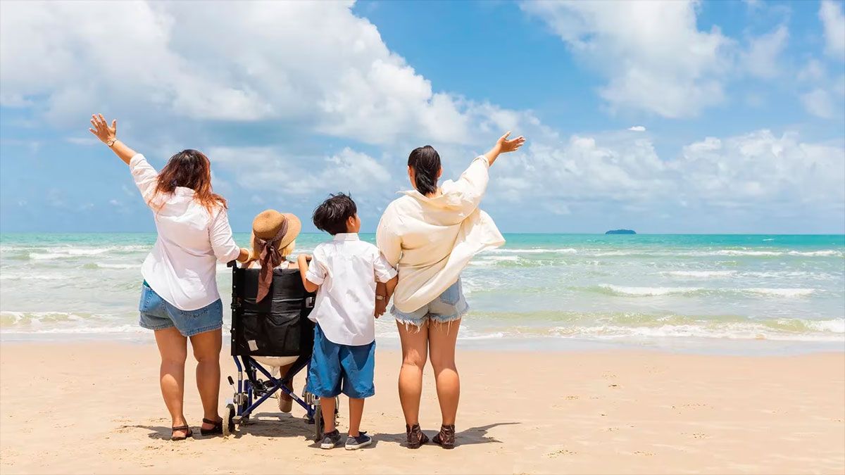 Familia en la playa con una persona en sillas de ruedas.